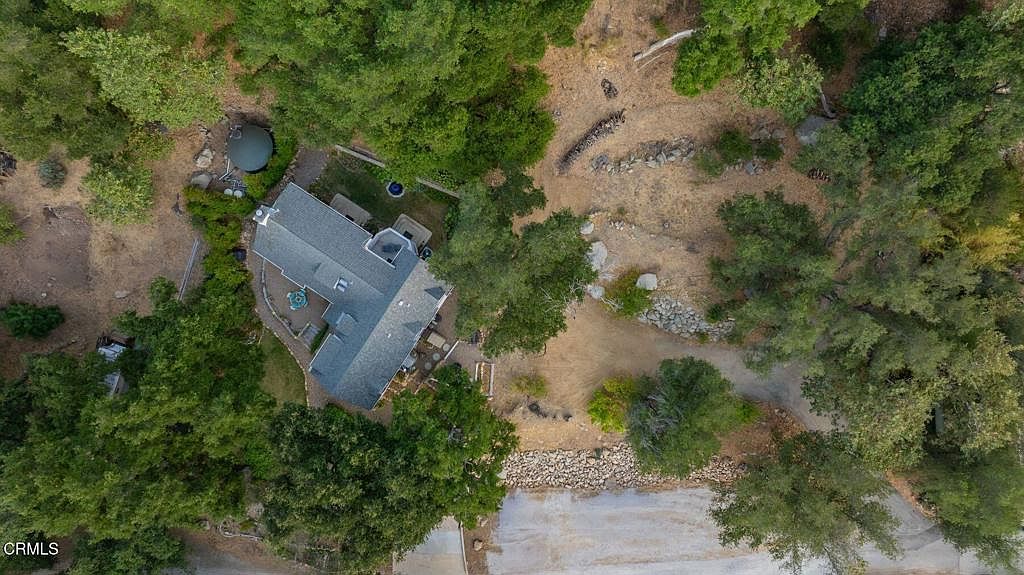 Aerial view of the cottage on its 3.2-acre parcel, creek and oaks framing the property
