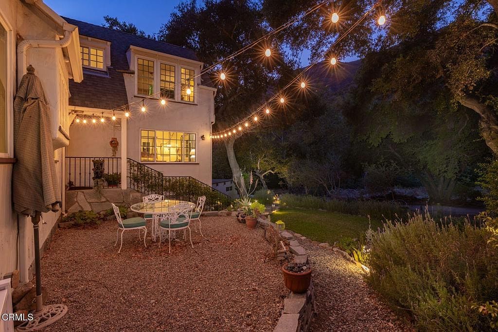 Twilight string lights over the dining patio with creek behind