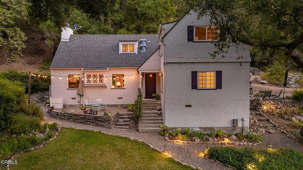 A 1926 cottage glowing at twilight, string lights crossing the patio under California oaks